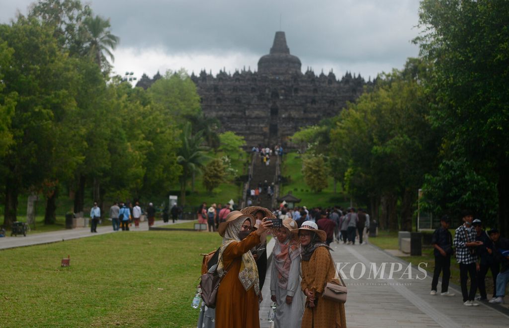 Wisatawan berfoto dengan latar belakang Candi Borobudur di Kabupaten Magelang, Jawa Tengah, Jumat (3/6/2022). Seiring dengan pelonggaran pembatasan sosial dan berjalannya kembali industri wisata juga turut menggerakkan perekonomian warga seperti pedagang kaki lima, warung, dan jasa. 