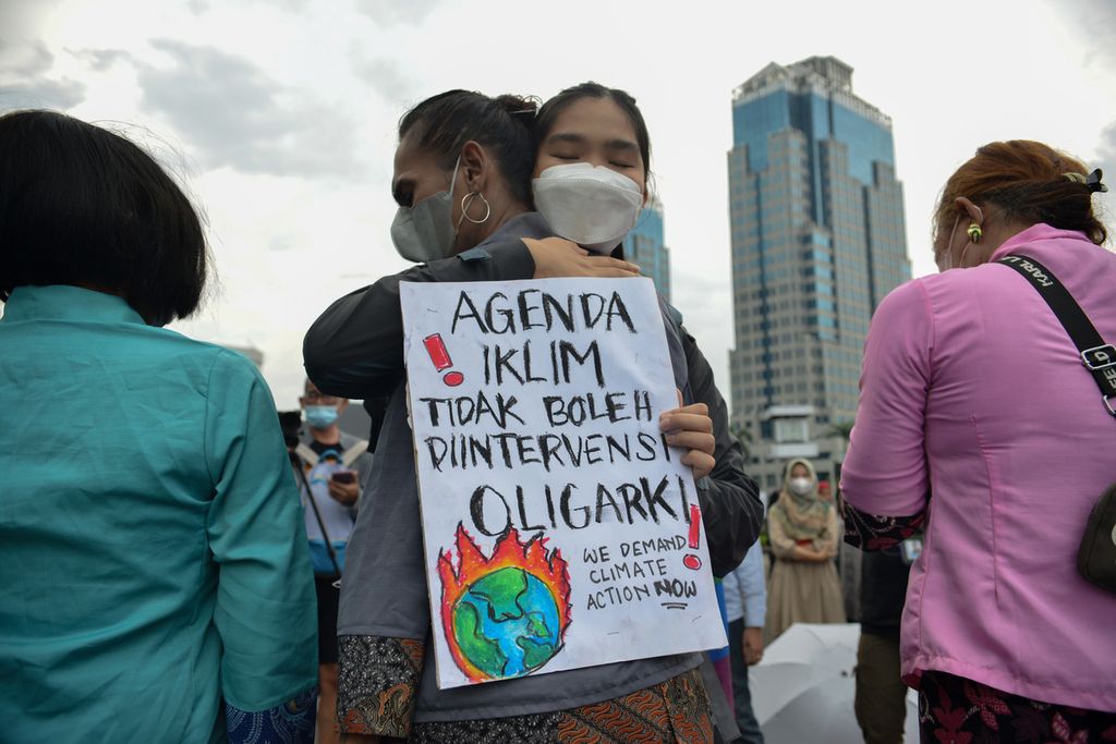 Massa aksi berpelukan saat teatrikal dalam aksi peduli krisis iklim di kawasan Patung Kuda Arjuna Wiwaha, Jakarta, Jumat (3/3/2023).