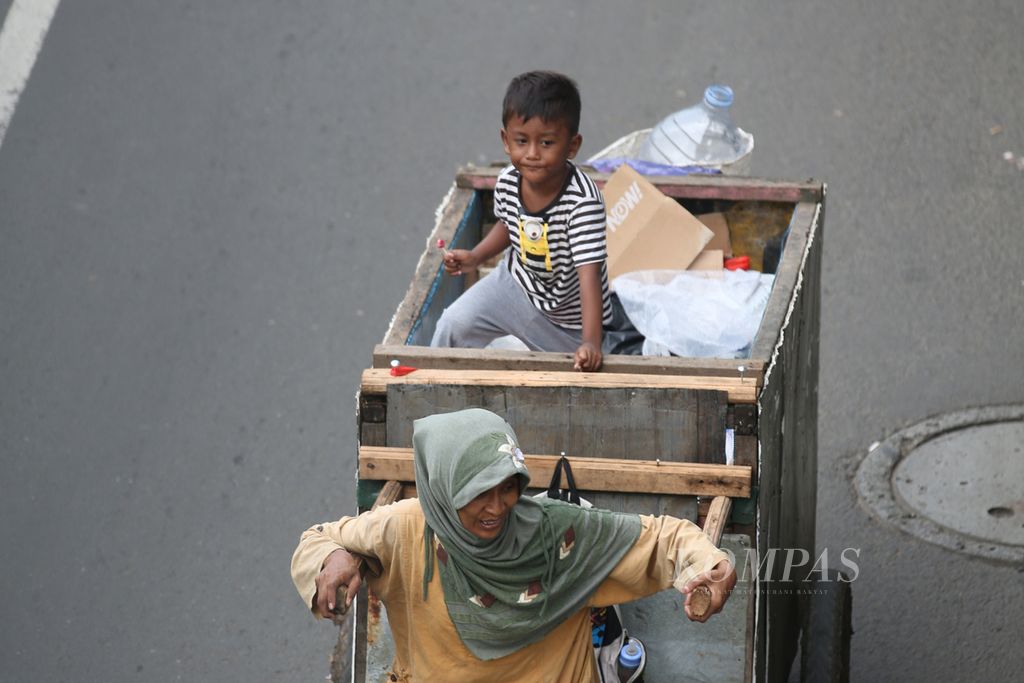 Pemulung mengajak anaknya memulung di kawasan Pulo Gebang, Jakarta Timur, Jumat (16/2/2024).