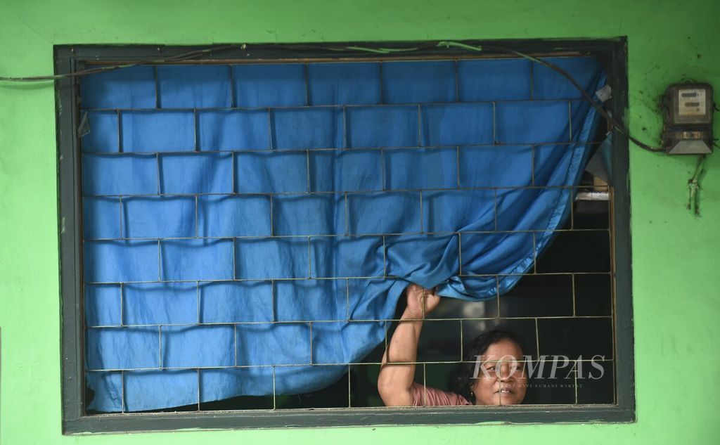Penjaga warung makan melihat dari balik jendela yang pecah pascaledakan di markas Detasemen Gegana Satuan Brimob Polda Jawa Timur di Jalan Gresik, Surabaya, Senin (4/3/2024). 