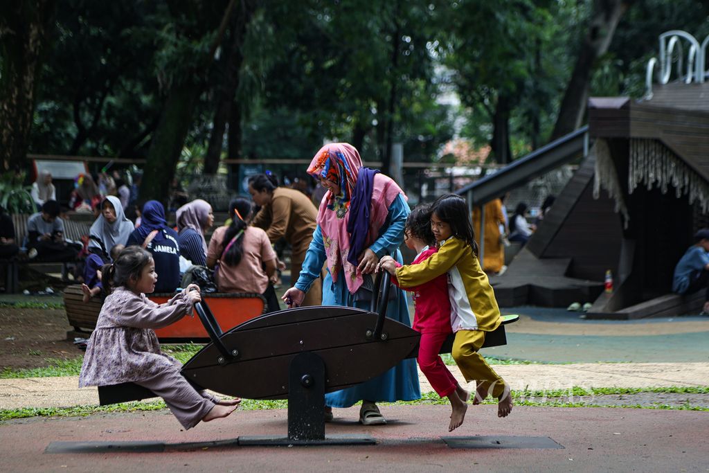 Orangtua mendampingi anak-anaknya bermain jungkat-jungkit di Tebet Eco Park, Jakarta Selatan, Jumat (12/4/2024).