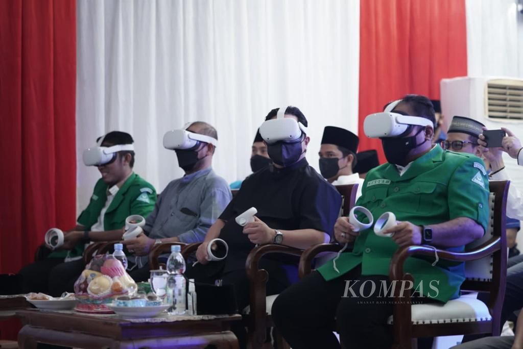 Dua dari kiri, Ketua KPU Hasyim Asy'ari, Menteri BUMN Erick Thohir, dan Ketum GP Ansor Yaqut Cholil Qoumas, mengenakan peranti penglihatan <i>virtual reality</i> dalam tasyakuran hari lahir GP Ansor Ke-88, Minggu (24/4/2022), di Jakarta.