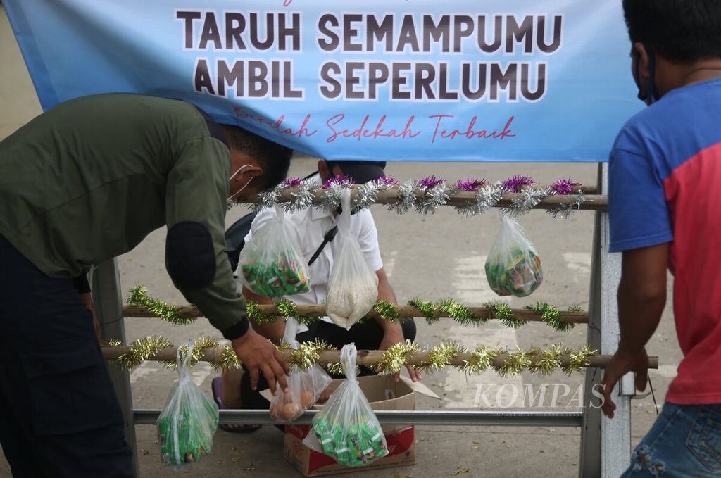 Warga meletakkan bungkusan bahan pokok seperti beras, mi instan, dan telur di sebuah rak besi yang diberi nama stasiun sedekah di Jalan Rasuna Said, Kunciran Jaya, Pinang, Tangerang, Banten, Rabu (20/5/2020). 