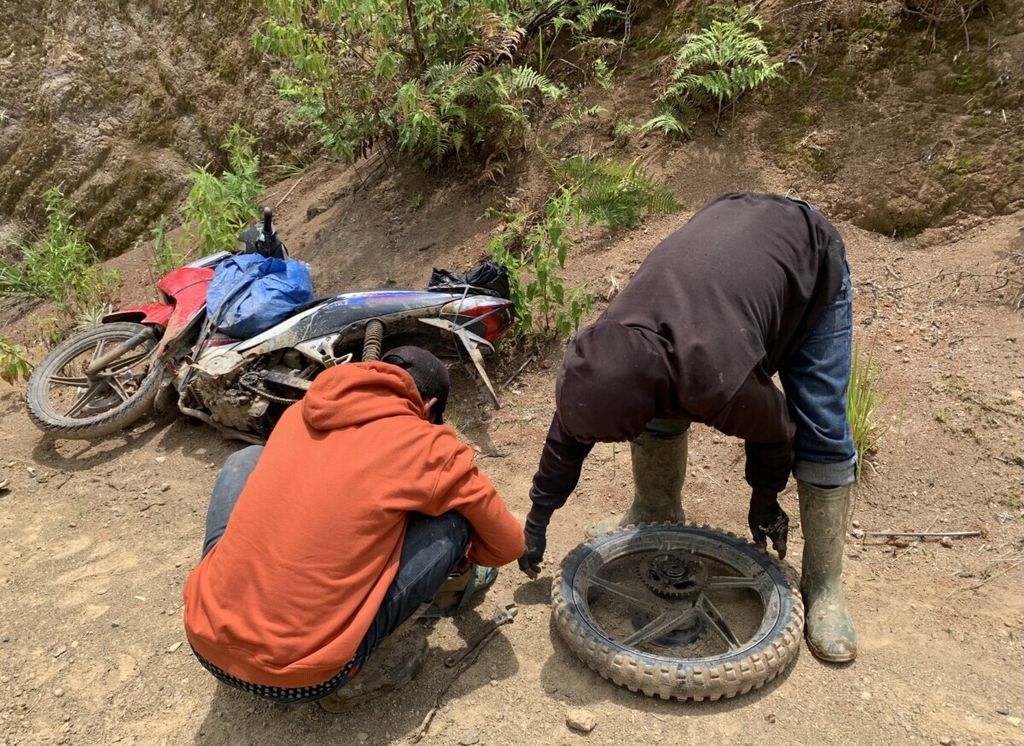 Dua pengojek bekerjasama menggangu ban motor yang rusak di wilayah Kecamatan Sabbang, Luwu Utara, Rabu (28/10/2021). Keejasama menjadi kata kunci dalam menjajal medan sulit di Seko, sebuah daerah terpencil di Luwu Utara, Sulawesi Selatan.