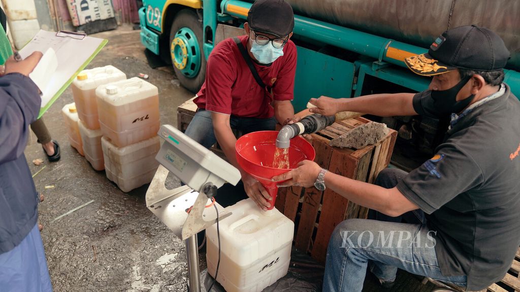 Officers fill jerry cans during the weekly distribution of bulk cooking oil at Perumnas Klender Market, East Jakarta, Friday (25/2/2022).