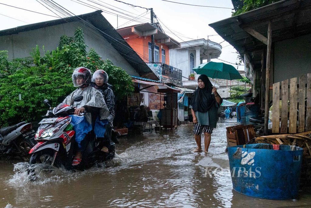 Warga melintasi salah satu ruas jalan yang tergenang banjir rob di Kelurahan Tanjung Uma, Kecamatan Lubuk Baja, Kota Batam, Kepulauan Riau, Rabu (25/1/2023). Curah hujan tinggi yang terjadi sejak Senin (23/1/2023) mengakibatkan banjir di beberapa titik di Batam.