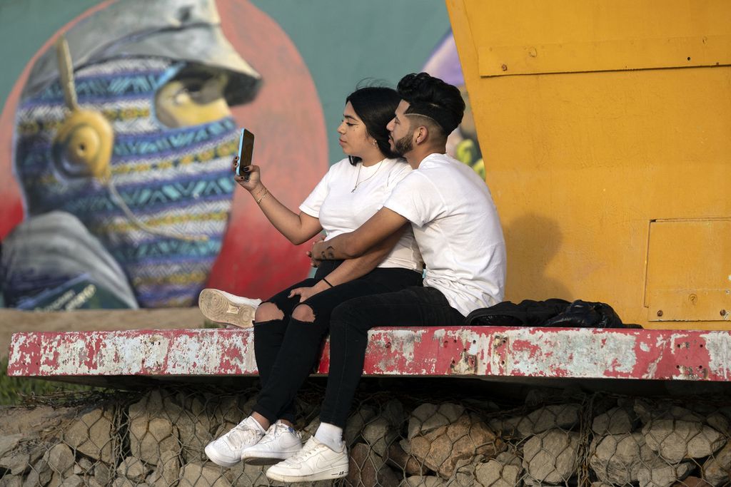 Sepasang kekasih duduk di menara penjaga pantai di Playas de Tijuana, Baja California, Meksiko, pada Hari Valentine, 14 Februari 2021. 