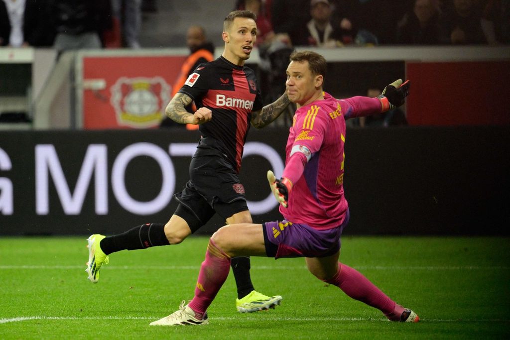 Pemain Bayer Leverkusen, Alejandro Grimaldo (kiri), mengecoh kiper Bayern Muenchen Manuel Neuer untuk mencetak gol pada laga Liga Jerman di Stadion BayArena, Leverkusen, Minggu (11/2/2024) dini hari WIB. Leverkusen menang 3-0 pada laga itu.