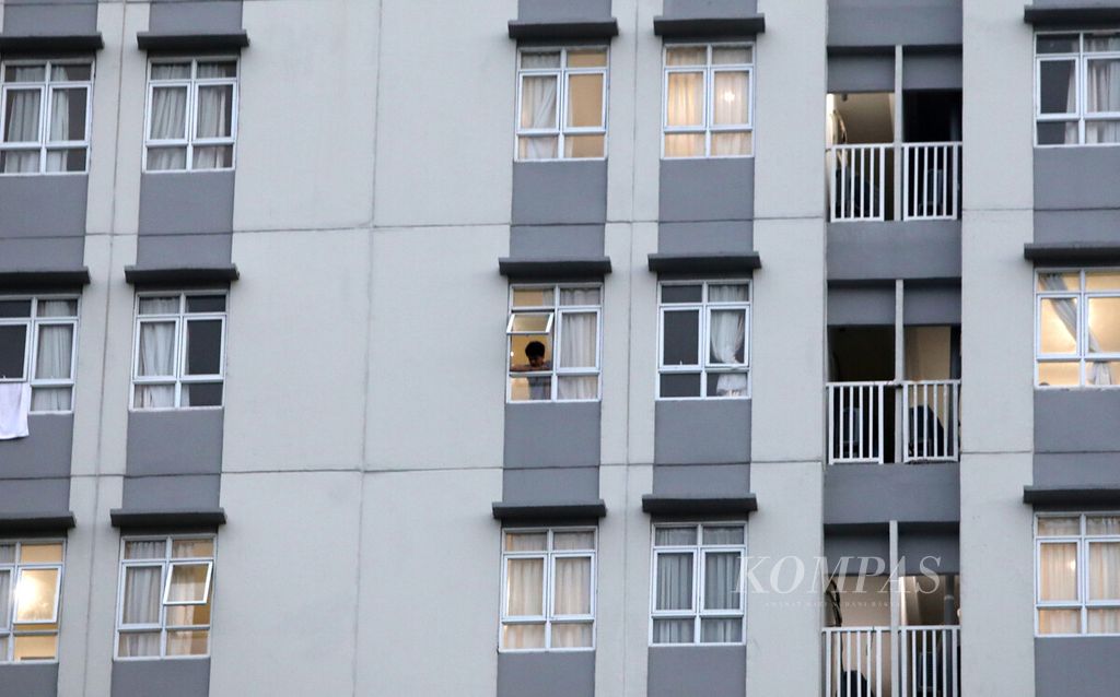 Pasien Covid-19 menengok dari jendela flat isolasi mandiri di salah satu menara dalam kompleks Rumah Sakit Darurat Wisma Atlet, Jakarta Pusat, Senin (30/11/2020). 