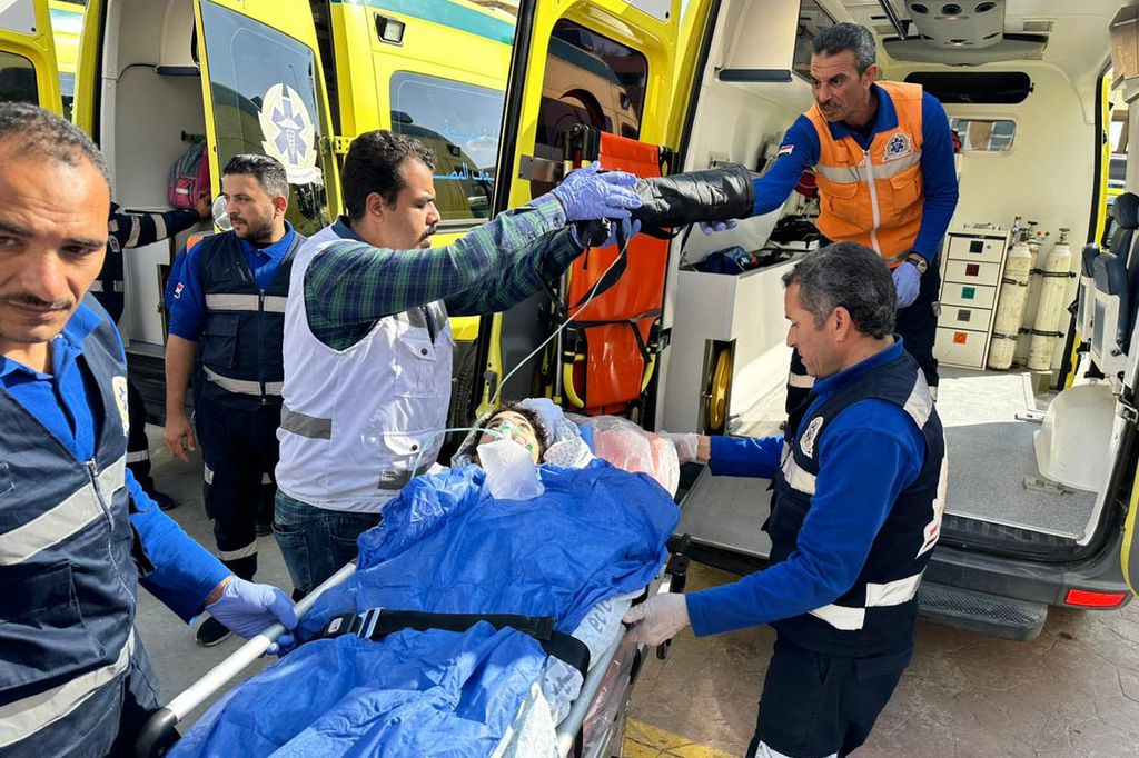 Seorang warga Palestina yang terluka diangkut dengan ambulans oleh tim paramedis Mesir di wilayah Mesir di area gerbang perbatasan Rafah, 6 Desember 2023. 
