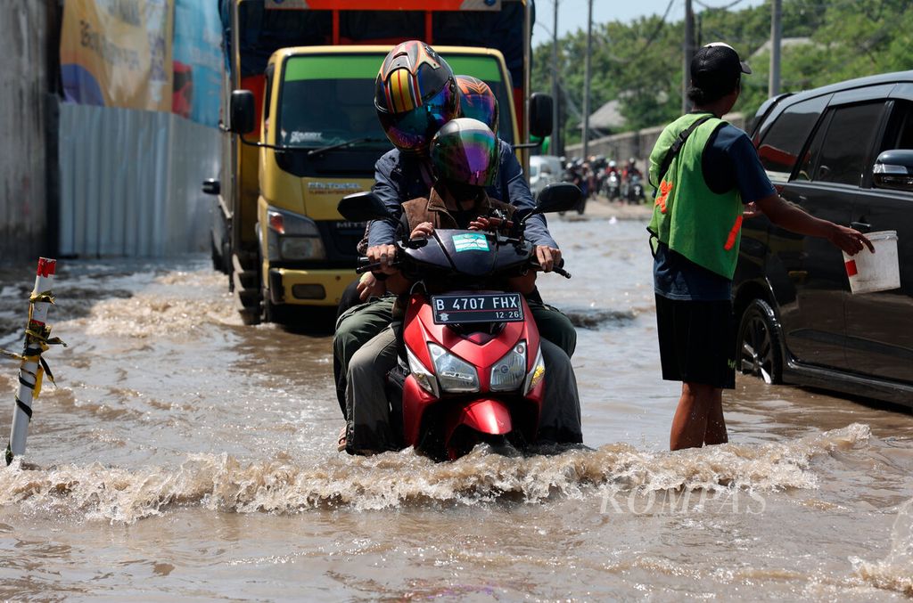 Pemudik motor saat melintasi genangan banjir di jalur pantura, Kaligawe, Kota Semarang, Jawa Tengah, Sabtu (6/4/2024). Banjir yang terjadi di kawasan tersebut berpotensi menyebabkan kemacetan panjang saat bersamaan dengan arus mudik. 