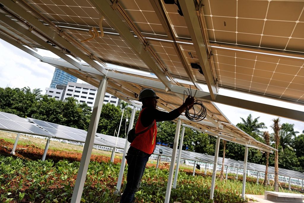 Pekerja menyelesaikan pemasangan surya panel di halaman kompleks Parlemen, Jakarta, Desember 2021. 