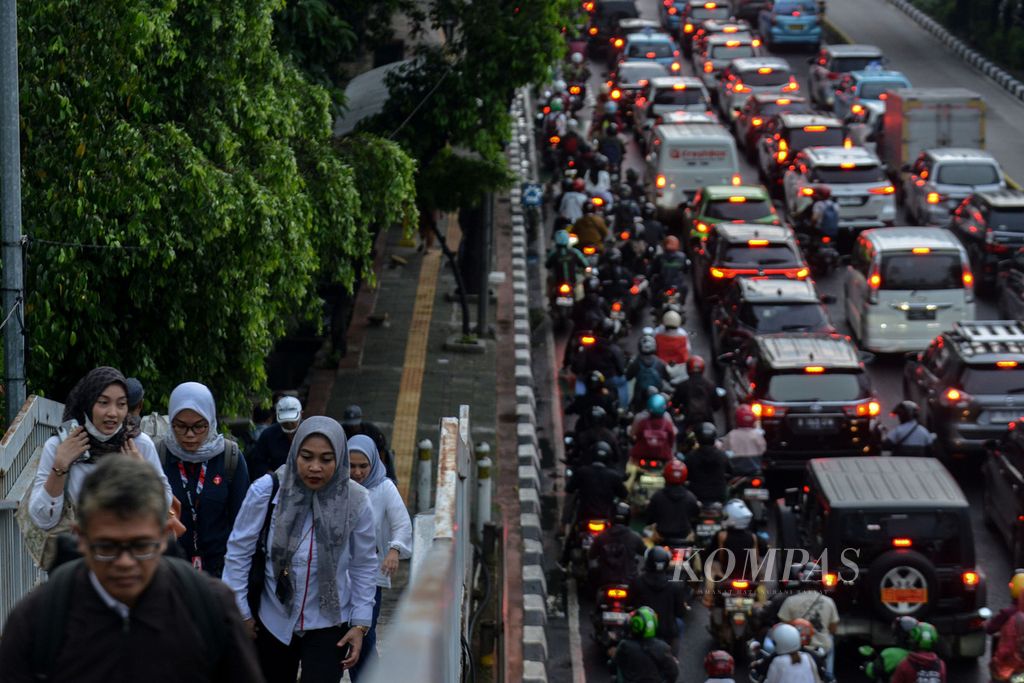 Para pekerja menaiki anak tangga jembatan penyeberangan orang di Jalan Gatot Subroto, Jakarta, saat jam pulang kerja pada Senin (19/6/2023).