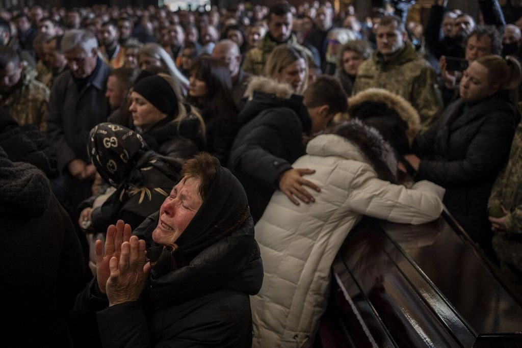 Para kerabat dan teman menghadiri upacara pemakaman untuk empat prajurit Ukraina yang tewas dalam serangan udara di pangkalan militer di Yarokiv di sebuah gereja di Lviv, Ukraina, Selasa (15/3/2022). 