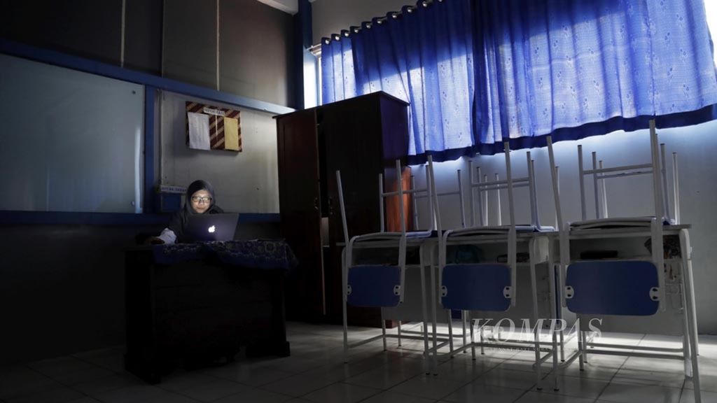 Kurnia Sari, guru kelas IX Madrasah Tsanawiyah Annajah, Petukangan, Jakarta, mengerjakan laporan harian di ruang kelasnya yang gelap akibat listrik padam, Senin (5/8/2019). 