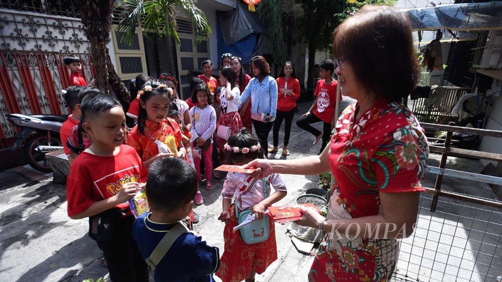 Warga membagikan angpao kepada anak-anak saat Hari Raya Imlek di Kampung Pecinan Tambak Bayan. Kecamatan Bubutan, Surabaya, Selasa (5/2/2019). Di kampung tersebut,  etnis Tionghoa, Jawa serta Madura berbaur sedemikian rupa.  