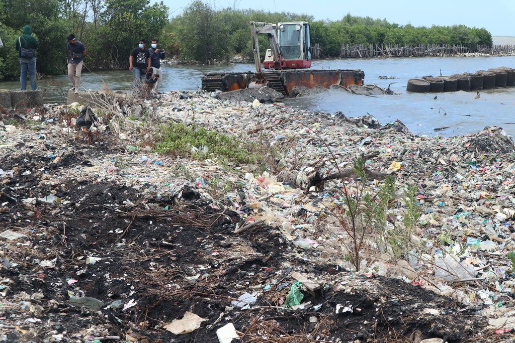 Ekskavator membersihkan tumpukan sampah dan sedimentasi di pertemuan Sungai Kedung Pane dan Pantai Kesenden, Kota Cirebon, Jawa Barat, Kamis (23/9/2021). Sampah tersebut menghambat aktivitas nelayan. Kapal nelayan baru melintas saat air pasang.
