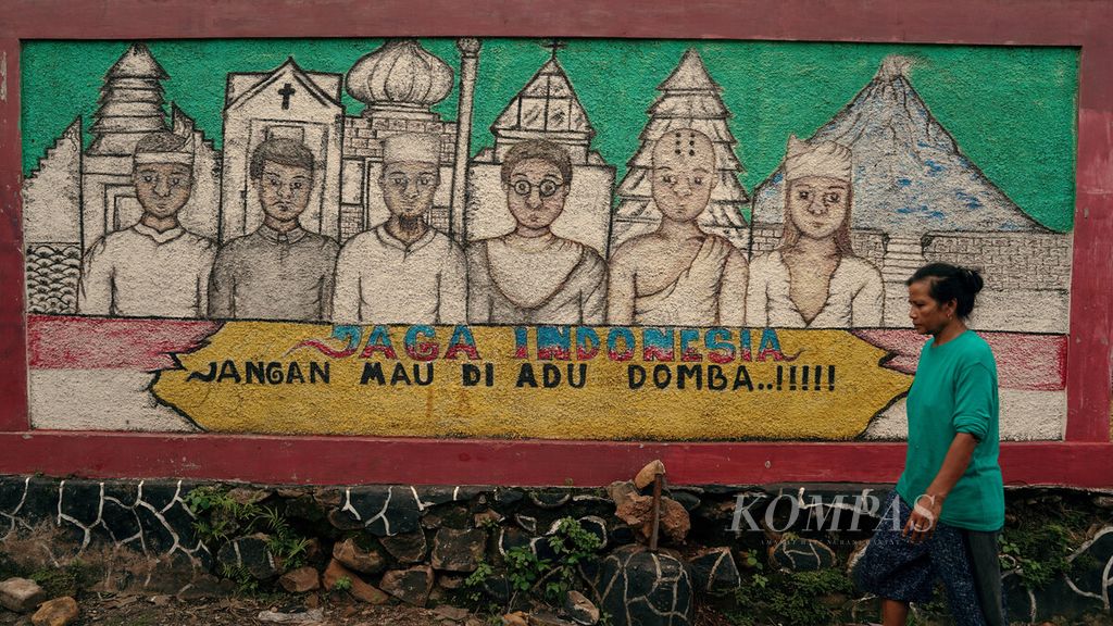 Warga melintasi mural bermacam penganut agama dan tempat peribadatan di CIkarang Barat, Kabupaten Bekasi, Jawa Barat, Selasa (3/5/2022). Mural tersebut menyuarakan meski ada perbedaan agama, Indonesia tetap harus dijaga dengan tidak mau diadu domba. 