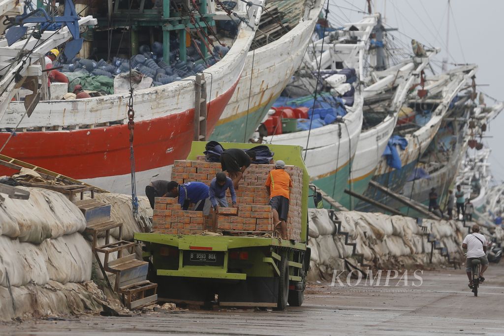 Daily workers lift goods to be put into wooden ship hulls at Sunda Kelapa Harbor, Pademangan, North Jakarta, Sunday (25/12/2022). The busy activity of loading and unloading of goods continues at the pinisi ship port even though it is a national holiday.