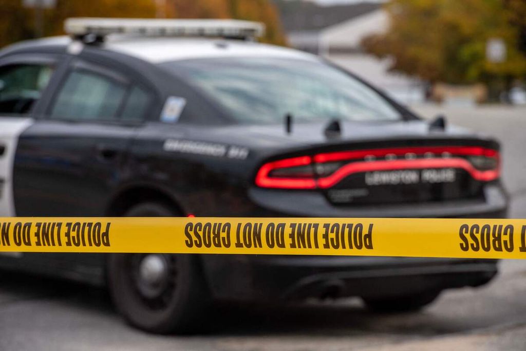 Satu unit mobil polisi menutup akses jalan menuju Sparetime Recreation, Kamis (26/10/2023) di Lewiston, Maine. Polisi tengah memburu tersangka penembakan massal itu. 