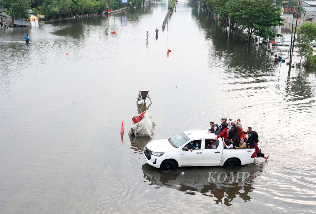 Kendaraan bak terbuka mengantarkan pekerja melintasi genangan banjir di Kaligawe, Kota Semarang, Jawa Tengah, Jumat (15/3/2024).