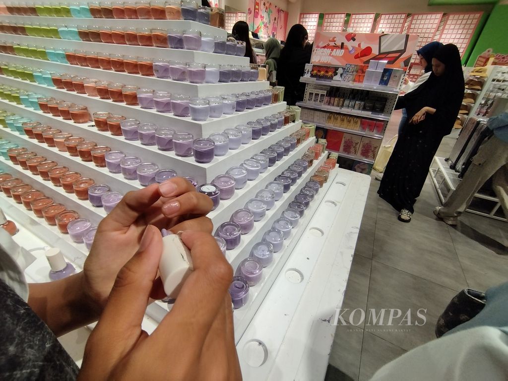 Pengunjung mencoba salah satu produk cat pewarna kuku yang dijual di salah satu toko ritel di pusat perbelanjaan di Tangerang Selatan, Banten, Minggu (30/12/2023).