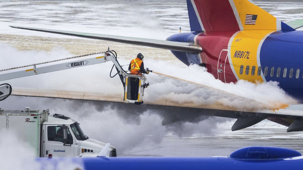 Kru Maskapai Soutwest Airlines tengah berupaya membersihkan salju yang ada di badan sebuah pesawat di Omaha, Nebraska, Rabu (21/12/2022). Ribuan penerbangan di Amerika Serikat terpaksa dibatalkan mulai Kamis (23/12/2022) karena badai salju. 