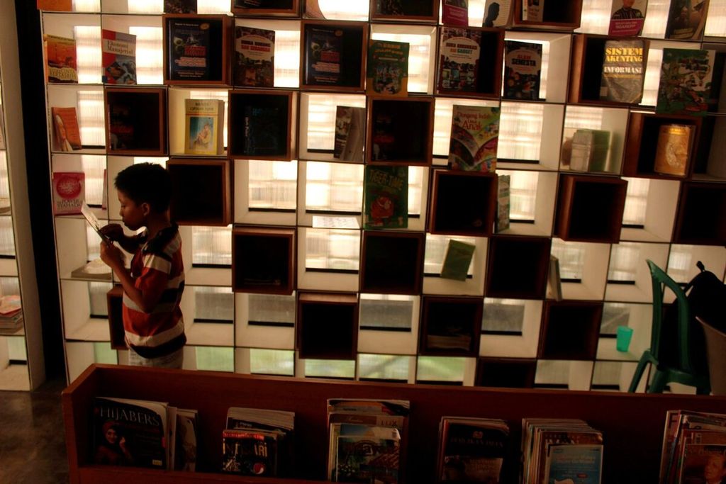 Seorang anak membaca buku di perpustakaan mini di Taman Bima, Kecamatan Cicendo, Kota Bandung, Jawa Barat, Senin (18/4). Keberadaan perpustakaan itu diharapkan menumbuhkan minat baca warga di sekitarnya.