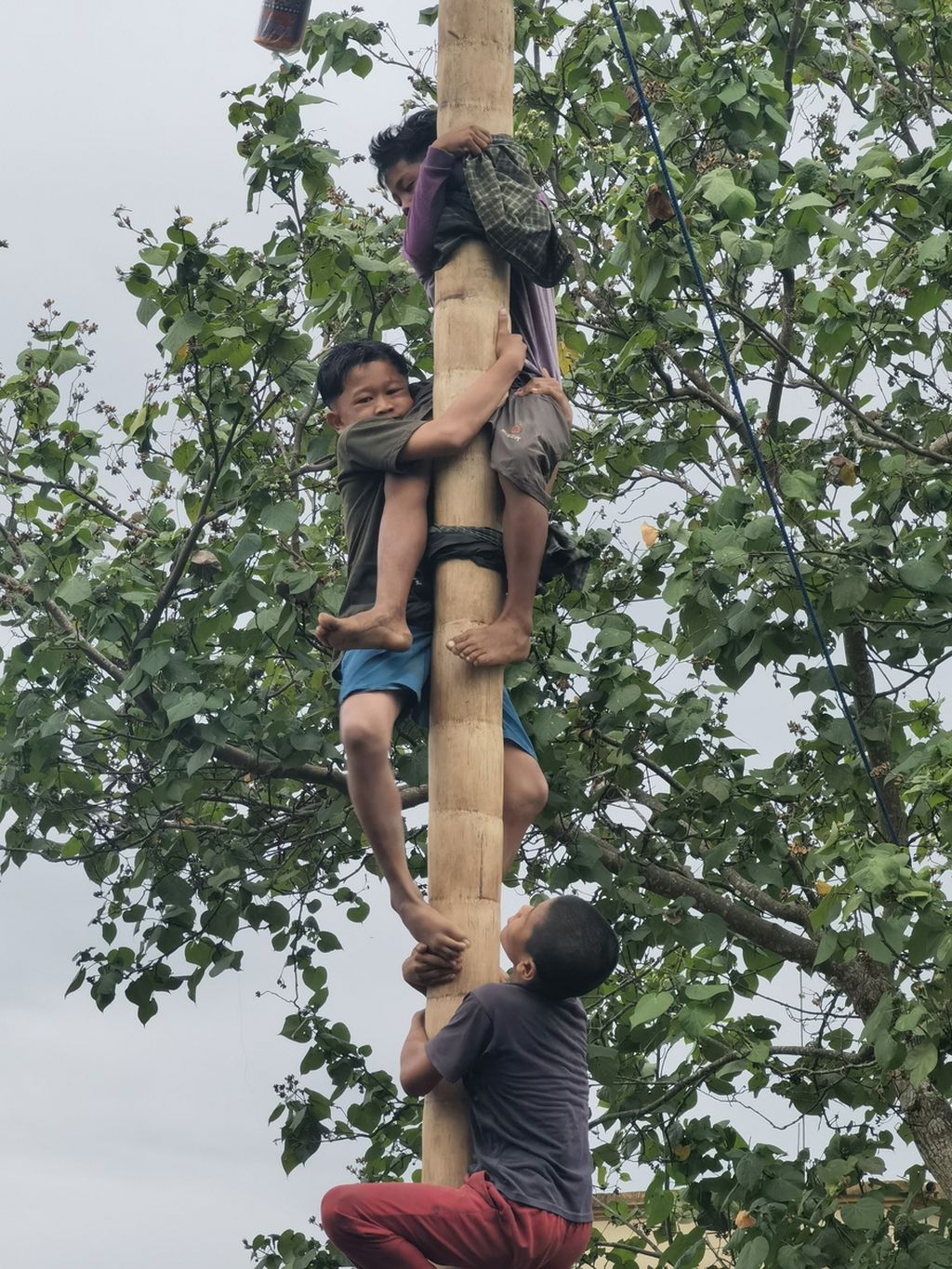 Para peserta saling membantu saat lomba panjat pinang di Dusun Kuang Jukut, Desa Pringgarata, Kabupaten Lombok Tengah, Nusa Tenggara Barat, Kamis (13/10/2022).