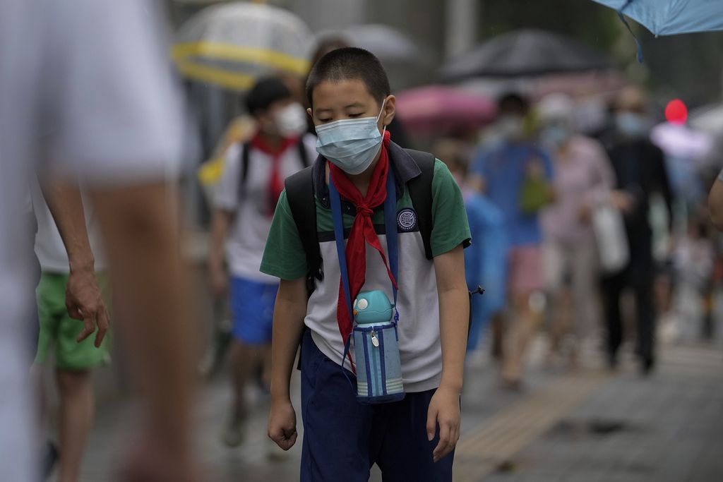 Seorang siswa sekolah dasar di Beijing menggunakan masker saat berangkat ke sekolah. Foto diambil pada Senin (27/6/2022).