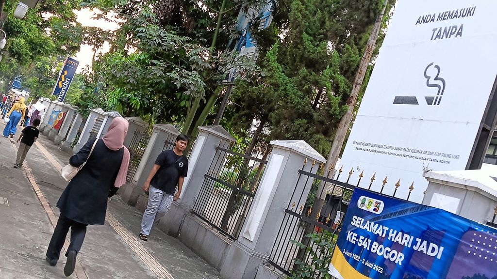 Warga melintasi jalur pedestarian di sekitar Jalan Kapten Muslihat, Kota Bogor, Jawa Barat, Kamis (29/6/2023). Di lokasi itu terpajang papan besar kawasan bebas asap rokok.