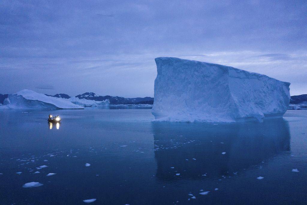 Perahu berlayar saat malam mendekati bongkahan es di bagian timur Greenland, 15 Agustus 2019.