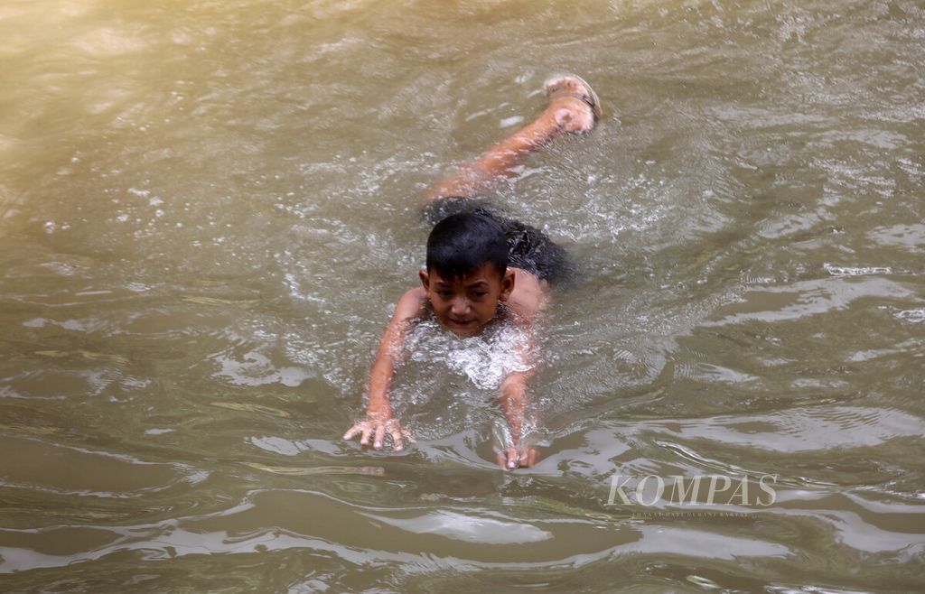 Anak-anak berenang di Kalimalang, Cipinang, Jakarta, saat cuaca panas, Selasa (25/4/2023). 