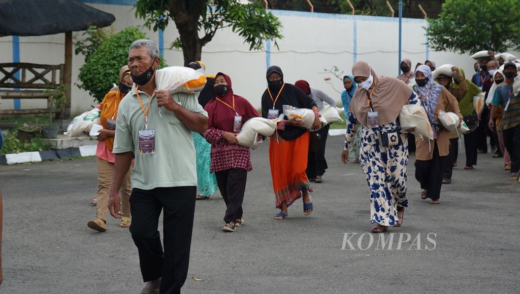 Para warga membawa beras bantuan pangan pemerintah yang diberikan oleh Presiden Joko Widodo di Gudang Perum Bulog Cabang Ngabeyan, di Kabupaten Sukoharjo, Jawa Tengah, Senin (10/4/2023). 