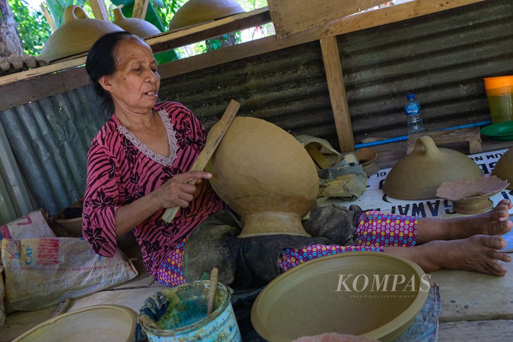 Using a bamboo stick and a river stone, Wa Aji (70) forms clay into earthenware, in Lipu Village, Betoambari, Baubau, Southeast Sulawesi, Thursday (26/5/2022). The existence of pottery in Buton land is threatened due to the absence of regeneration of pomanduno or earthenware makers.