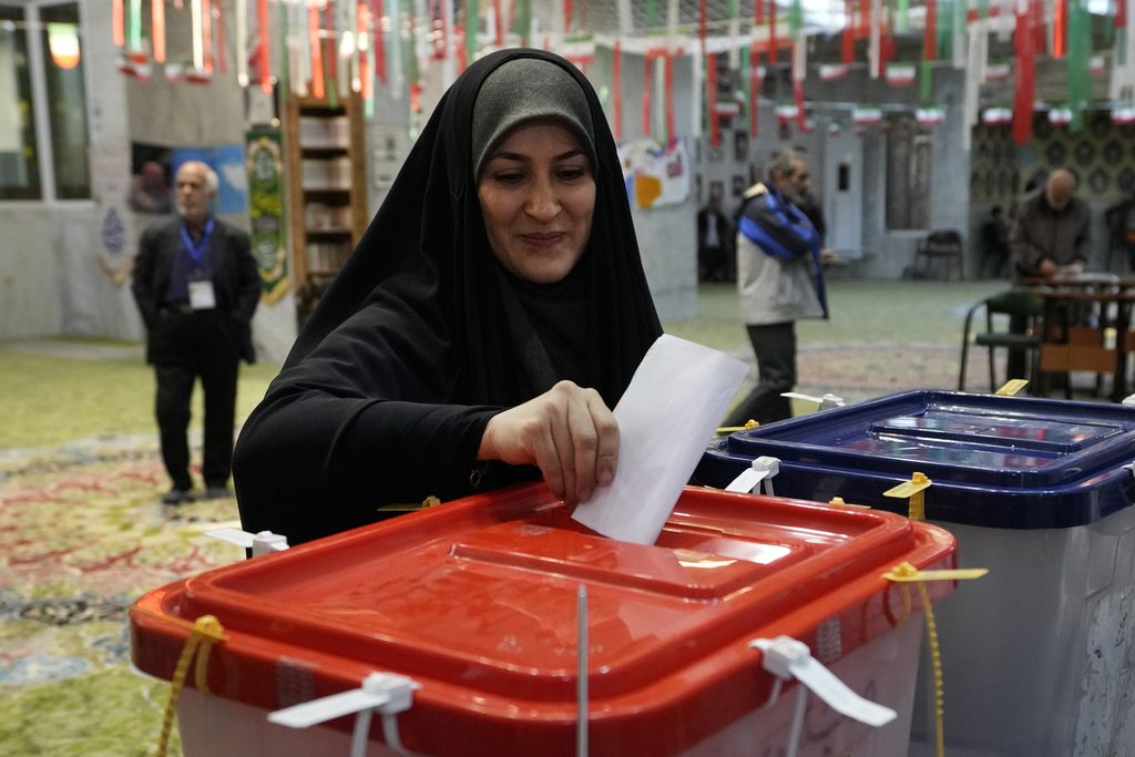Seorang perempuan warga Iran memasukkan surat suara seusai menggunakan hak suaranya di sebuah tempat pemungutan suara di Teheran, Iran, Jumat (1/3/2024).  