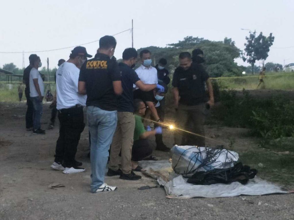 Polisi memeriksa sesosok mayat di dalam karung di kolong Tol Cibitung-Cilincing, Jakarta Utara yang ditemukan pada Sabtu (27/5/2023).