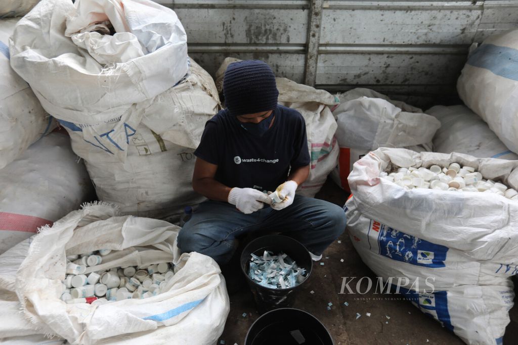 Pekerja melepas label pada botol bekas kosmetik di penyedia jasa pengolahan sampah Rumah Pemulihan Material Waste4Change Bekasi 2.0 di kawasan Padurenan, Mustika Jaya, Bekasi, Jawa Barat, Selasa (8/3/2023).