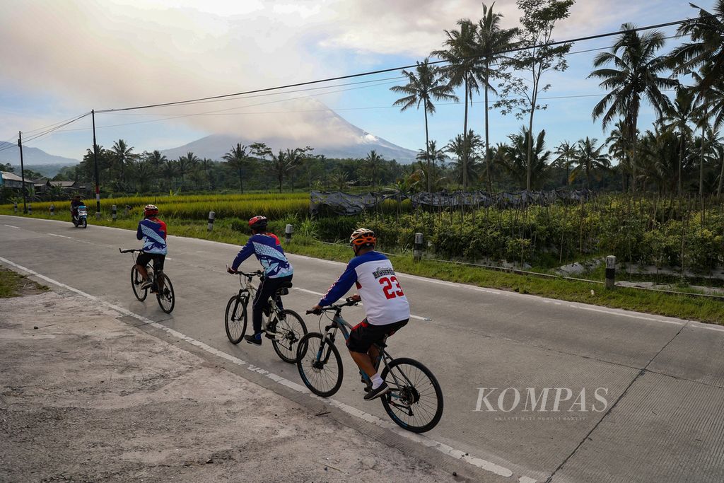 Pesepeda melintas saat terjadi erupsi Gunung Merapi di Desa Krogowanan, Sawangan, Magelang, Jawa Tengah, Minggu (12/3/2023). 