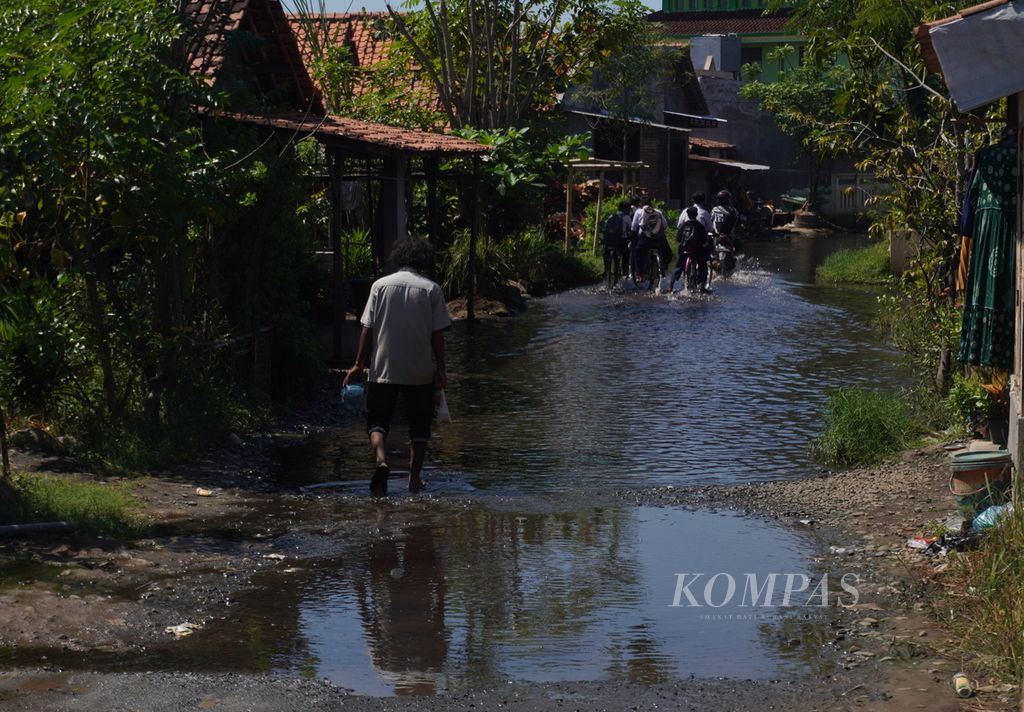 Warga melintas di tengah genangan rob di Kelurahan Pasirkratonkramat, Pekalongan Barat, Kota Pekalongan, Jawa Tengah, Selasa (18/7/2023). Banjir rob rutin melanda sejak 2014 dan di sebagian tempat, rob tak pernah surut.