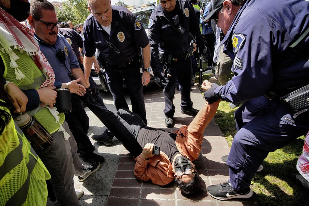 Seorang pengunjuk rasa dari Universitas Southern California ditahan petugas Departemen Keamanan Publik USC selama pendudukan pro-Palestina di Taman Alumni kampus itu, di Los Angeles, Amerika Serikat, Senin (24/4/2024).