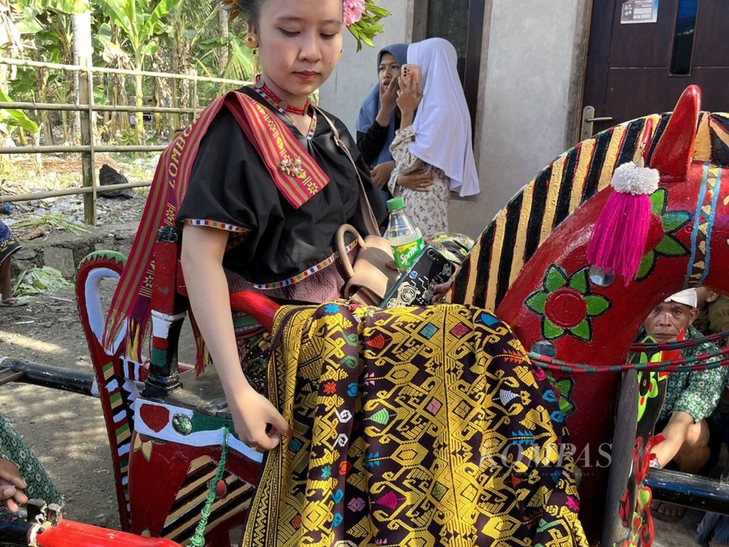 Seorang perempuan memakai kain tenun yang dihasilkan warga Desa Sukarara, Kecamatan Jonggat, Lombok Tengah, NTB, Kamis (6/7/2023). Kain tenun dengan aneka motif digunakan warga Sukarara untuk upacara adat, seperti pernikahan.