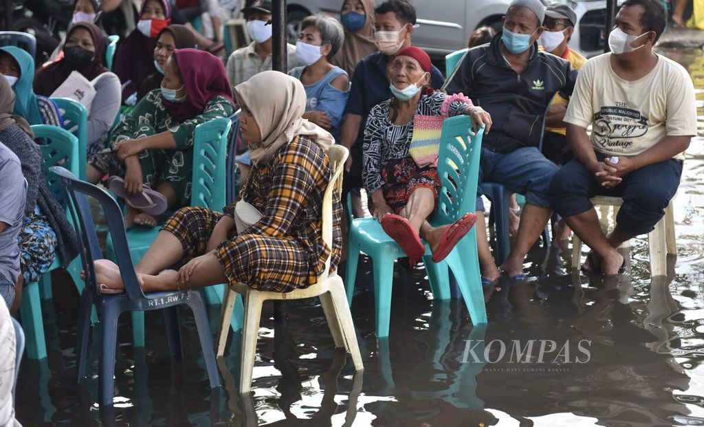 Warga antre mendapatkan Bantuan Langsung Tunai (BLT) minyak goreng saat banjir rob di halaman Markas Koramil 0830/01 Krembangan, Kota Surabaya, Jawa Timur, kamis (19/5/2022).
