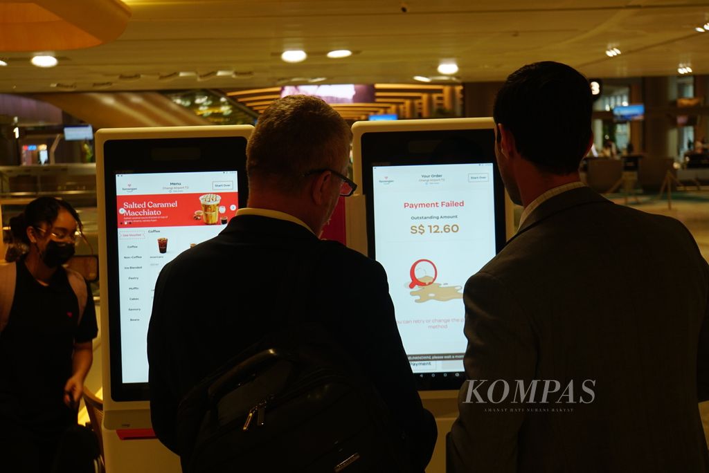 Pengunjung mencoba memesan kopi melalui layar interaktif di gerai Kenangan Coffee kedua di Singapura yang dibuka di Terminal 2 Bandara Changi, Rabu (27/9/2023).