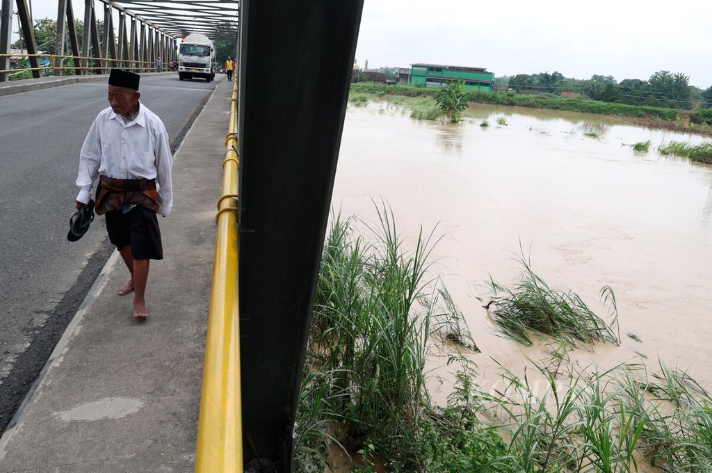 Residents cross a bridge during the overflowing of Tuntang River in Gubug Village, Gubug District, Grobogan Regency, Central Java on Tuesday (6/2/2024). The flood from the overflowing Tuntang River since early morning caused road access to be cut off, the river embankment to break, and inundate residential areas and public facilities. As a result of the flood, some traffic was diverted to alternative routes.