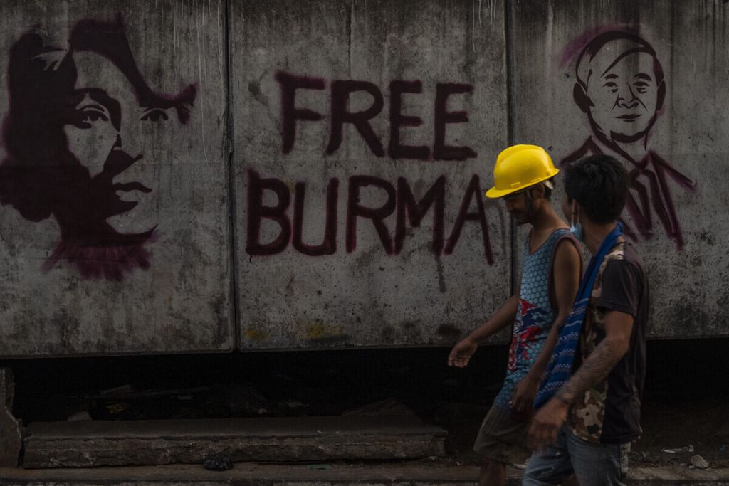 Dua pekerja melewati sebuah tembok bertuliskan Bebaskan Burma” di Yangon, Myanmar, Rabu (17/3/2021). 