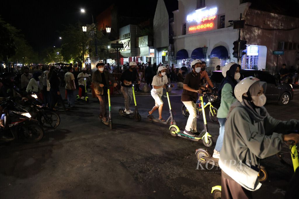 Wisatawan menikmati suasana malam dengan naik skuter listrik di kawasan wisata Malioboro, Kota Yogyakarta, Selasa (28/12/2021). 