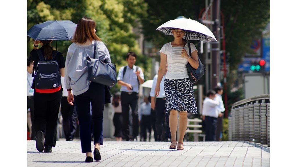 Pejalan kaki berjalan di bawah terik matahari selama musim gelombang panas di Tokyo, Jepang, Kamis (2/8/2018).