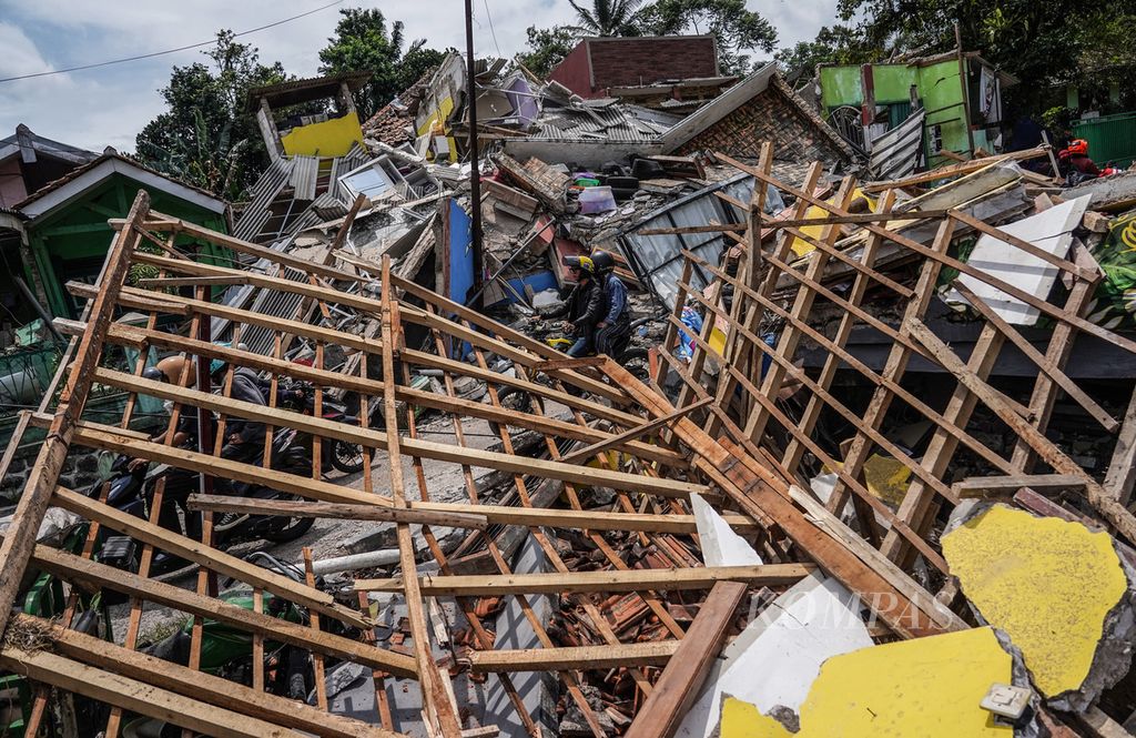 Warga melintasi reruntuhan di Desa Gasol, Cugenang, Kabupaten Cianjur, Jawa Barat, Selasa (22/11/2022). Kondisi kerusakan akibat gempa yang melanda Cianjur pada Senin (22/11/2022) terlihat pada sejumlah wilayah desa yang terdampak. 