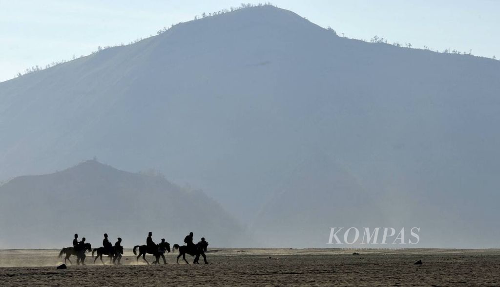 Wisatawan naik kuda melintasi hamparan pasir di kaldera Tengger. 